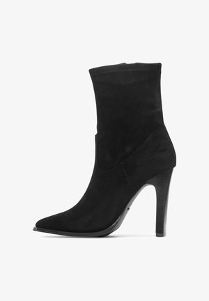 Czarny zamszowy botek z ostrym noskiem, wysokim smukłym obcasem i cholewką do połowy łydki.