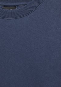 Sweat-shirt bleu marine à col rond avec col côtelé et tissu tricoté lisse, montrant un gros plan du haut de la poitrine et de la zone du cou.