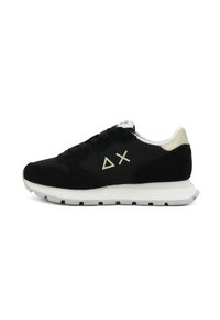 Scarpa sportiva nera con upper in camoscio e rete, suola intermedia bianca, dettagli dorati sul tallone, caratterizzata da un logo astratto sul lato, design con lacci.