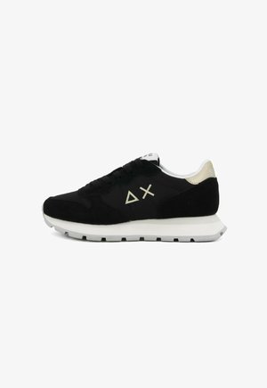 Scarpa sportiva nera con upper in camoscio e rete, suola intermedia bianca, dettagli dorati sul tallone, caratterizzata da un logo astratto sul lato, design con lacci.