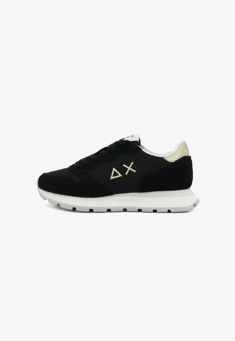 Scarpa sportiva nera con upper in camoscio e rete, suola intermedia bianca, dettagli dorati sul tallone, caratterizzata da un logo astratto sul lato, design con lacci.
