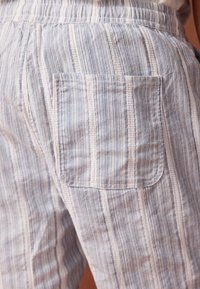 Lichtgewicht broek van gestreept stof in blauw en wit, met een standaard achterzak, elastische tailleband en een zachte textuur.