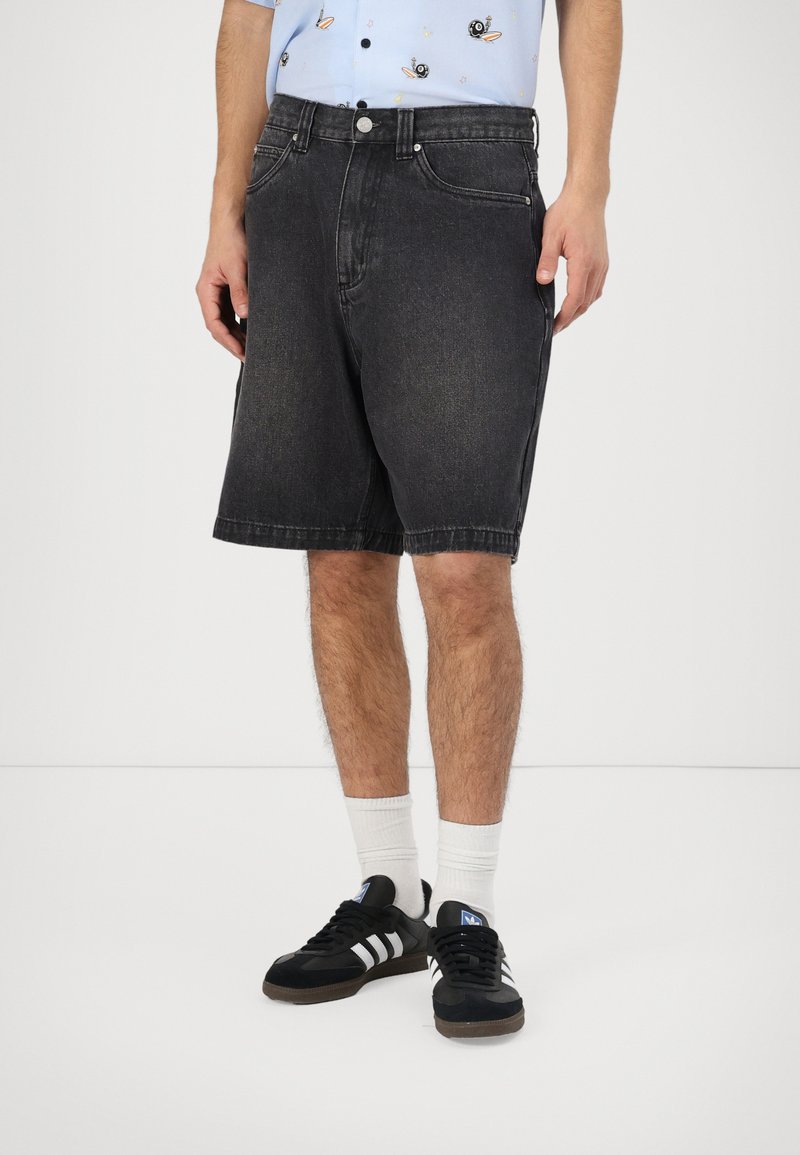 Black denim shorts with a straight cut, five-pocket design, and subtle faded detailing, paired with black sneakers and white socks.