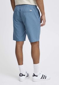 Plave kratke hlače napravljene od laganog materijala s elastičnom waistband, dva bočna džepa i jedan stražnji džep. Završene su s čistim rubom.