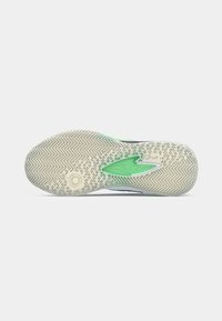 Semelle de chaussure avec un motif en caoutchouc texturé, mettant en avant un accent vert et un design de semelle circulaire. Des couleurs grises claires et blanches crèmes dominent.