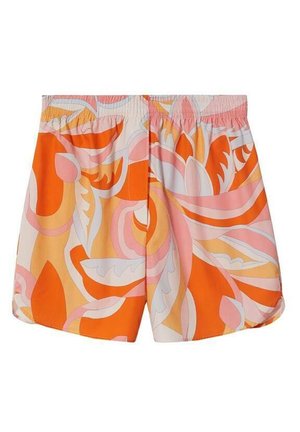 Persona que lleva una camisa blanca abotonada con las mangas remangadas, pantalones cortos con un patrón multicolor en naranja y rosa, y zapatos de tacón alto transparentes.