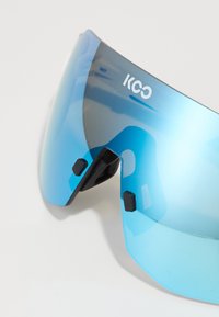 Sonnenbrille mit blauen Verlaufsgläsern, halbrahmenlosem Design und schwarzen Gummi-Nasenpads. Logo oben links auf dem Glas angebracht.