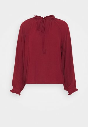 Langærmet bordeauxbluse med flæsekant ved krave og manchetter, med bindebånd ved halsudskæringen og løs pasform.