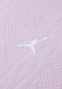 Svetloružová textúrovaná látka s bielym vyšívaným logom Jumpman, s diagonálnymi vzormi a jemným vzhľadom.