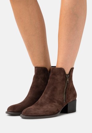 Brązowe zamszowe botki za kostkę z okrągłym noskiem i zamkiem błyskawicznym z boku, z wystającym obcasem i gładką teksturą.