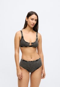 Μαγιό δύο τεμαχίων από σκούρο, ριμπ ύφασμα. Το πάνω μέρος έχει λαιμόκοψη scoop και μεταλλική λεπτομέρεια στο κέντρο. Κάτω μέρος με ψηλόμεσο σχεδιασμό.