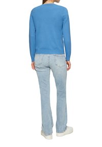 Hellblauer Strickpullover mit langen Ärmeln, rundem Halsausschnitt und geripptem Saum, kombiniert mit hellblauen Jeans und weißen Turnschuhen.