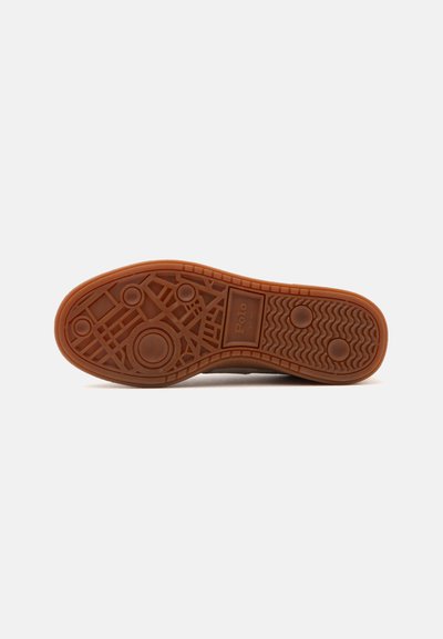 Sole of a brown Polo sneaker with geometric patterns, circular grips, and a rectangular logo area visible on a plain white background.