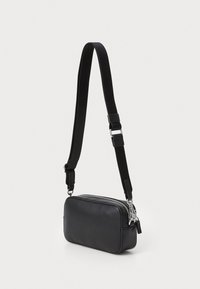 Svart läder crossbody-väska med rektangulär form, dragkedjestängning och justerbar canvasrem. Har metalliska dragkedjor och hårdvaruackcenter.