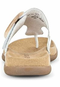 Tongs en cuir blanc avec une semelle intérieure texturée, une semelle en caoutchouc marron et un accent décoratif circulaire sur la bride.
