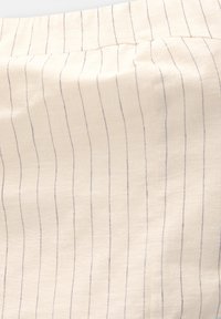 Tessuto beige chiaro con strisce verticali blu navy, caratterizzato da una texture morbida e un aspetto tessuto, ideale per abbigliamento o rivestimenti.