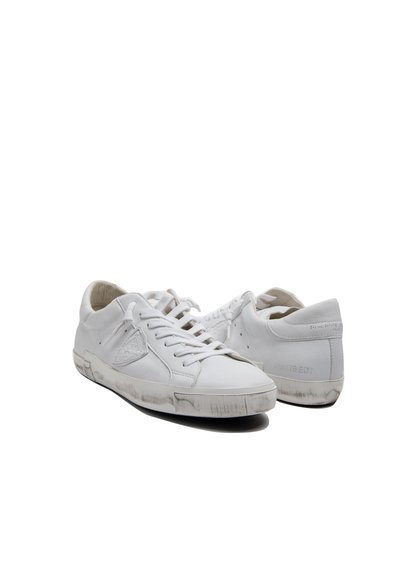 Baskets en cuir blanc avec un design basse, dotées de lacets plats, d'une marque discrète et d'une semelle en caoutchouc légèrement usée.