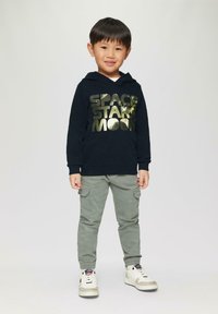 Navy hoodie met metallic gouden tekst "SPACE STARS MOON," gecombineerd met lichtgrijze cargobroek en witte hoge sneakers.