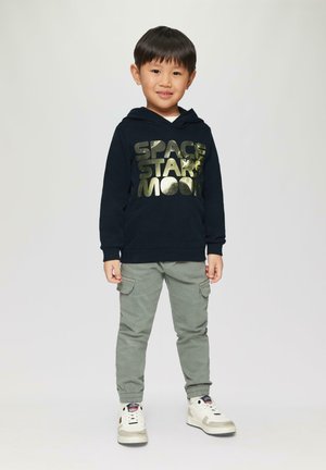 Granatowy hoodie z metalicznie złotym napisem "GWIAZDY PRZESTRZENNE KSIĘŻYC", w połączeniu z jasnoszarymi spodniami cargo i białymi trampkami za kostkę.