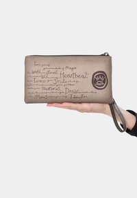 Cartera de cuero marrón con superficie texturizada, que presenta texto en estilo manuscrito y un logotipo circular. Incluye una correa de muñeca y cierre de cremallera.