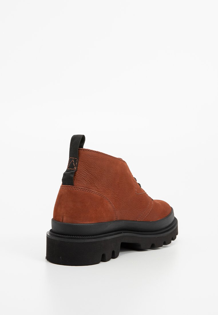 Bottine en cuir marron avec semelle épaisse à relief noire et tirant au talon noir, vue depuis l'arrière gauche sur fond blanc.