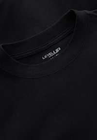 Schwarzes Rundhals-T-Shirt, das den Kragen und das Innenetikett mit dem weißen Markentext "LEVEL UP" zeigt.