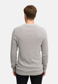 Pull en tricot gris avec un motif texturé, à manches longues et col rond. Les poignets et l'ourlet côtelés renforcent la coupe ajustée.