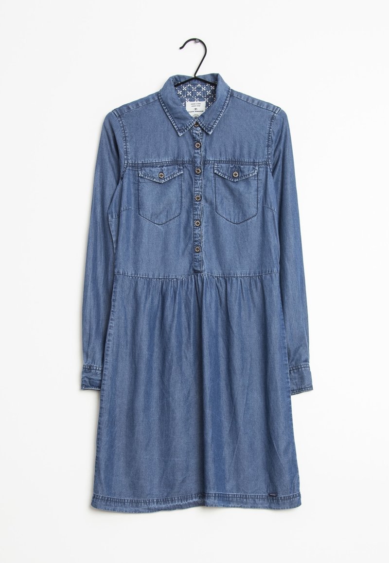 Robe en jean à manches longues avec fermeture boutonnée sur le devant, deux poches poitrine à boutons et taille froncée, accrochée sur un cintre noir.