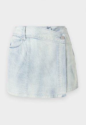 Jupe portefeuille en denim bleu clair avec fermeture boutonnée à l'avant, passants pour ceinture et poches latérales, présentée sur un fond uni.