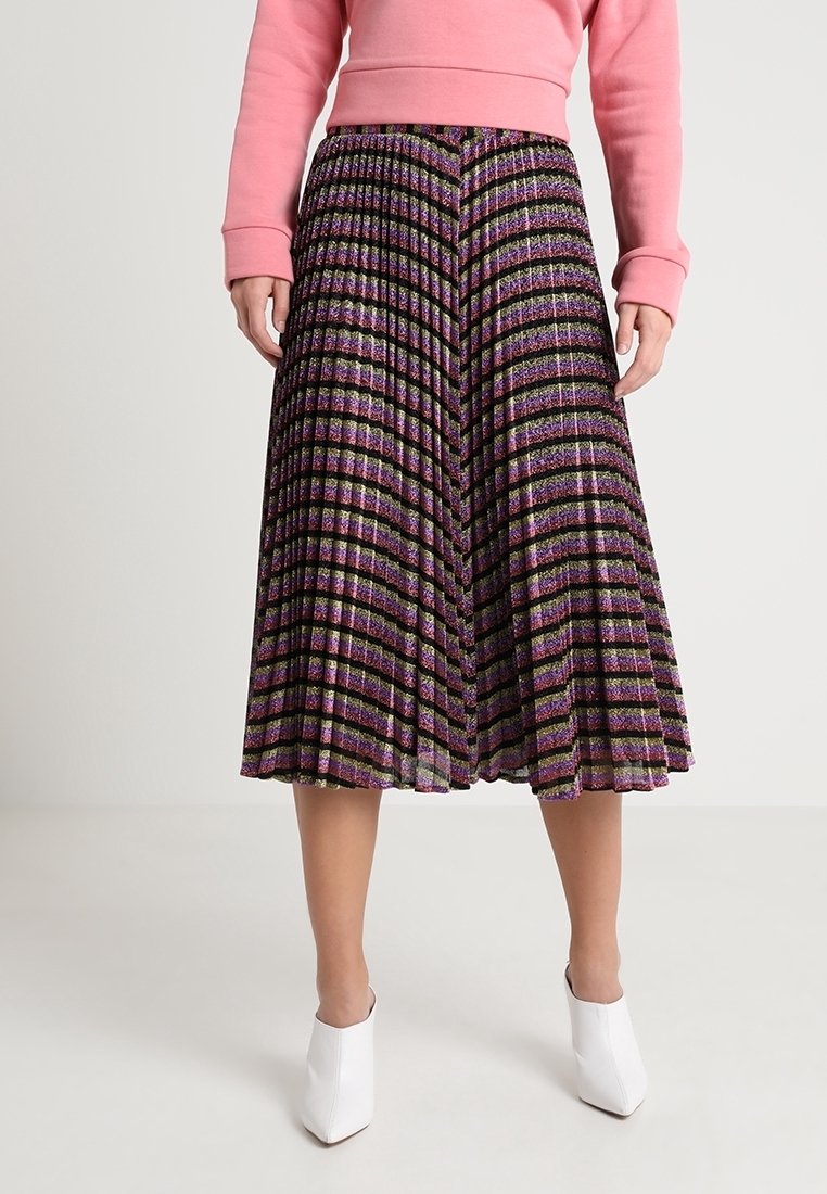 Falda negra plisada con patrones de rayas moradas y verdes, con un acabado texturizado. Combinada con un sudadera rosa y tacones blancos.