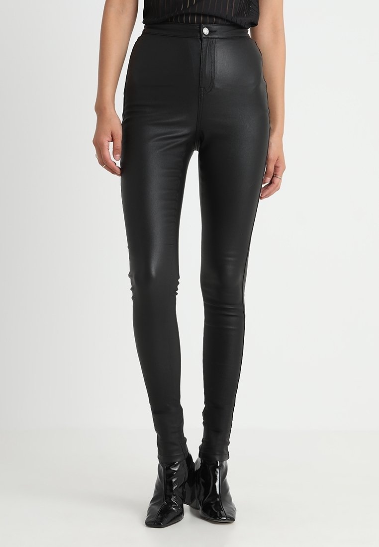 Leggings de imitación piel negra de cintura alta con una textura suave, con cierre de cremallera y botón, silueta ajustada y diseño elegante.