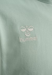 Ljusgrön bomullströja med en broderad bi-logotyp och ordet "hummel" i vitt. Slät textur, rundad halsdesign.