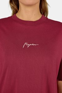 Tumši sarkans kokvilnas T-krekls ar apaļu izgriezumu, kurā ir neliels, balts izšūts skripts "Regalov" uz krūšu. Gluda tekstūra, īsas piedurknes.