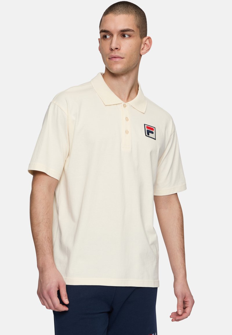Polo de manga corta en beige de algodón con tapeta de botones y logo bordado en el lado izquierdo del pecho. Textura suave, ajuste clásico.