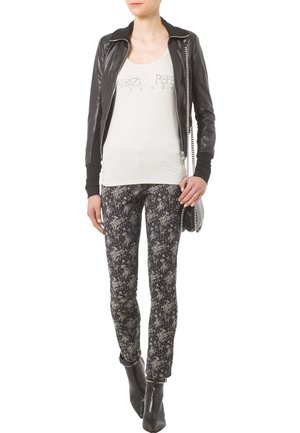 Chaqueta de cuero negra con cremallera, camiseta sin mangas blanca con estampado y pantalones skinny negros con motivo. Combinados con botas negras hasta el tobillo. Acentos metálicos en plata.