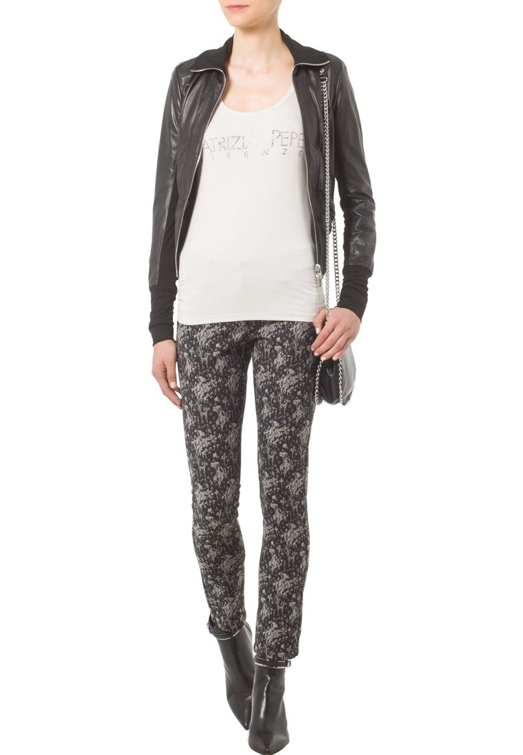 Czarna skórzana kurtka na zamek, biała koszulka na ramiączkach z nadrukiem oraz czarne, wzorzyste rurki. Noszone z czarnymi botkami za kostkę. Srebrne akcenty metalowe.