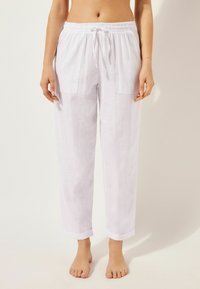 Pantalons en lin blancs avec une taille élastiquée à cordon, deux poches avant et des ourlets roulés ; texture légère et respirante.
