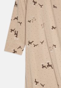 Chemise beige avec un motif éparpillé de rennes marron et de points noirs, fabriquée en tissu doux, avec des manches longues et un col rond.