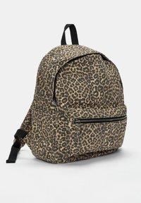 Rucsac cu imprimeu de leopard, confecționat din pânză, cu o formă rotundă, având un buzunar frontal cu fermoar și bretele negre ajustabile.