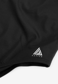 Schwarze Sportshorts aus glattem, elastischem Stoff mit einem weißen Logo im geometrischen Design am unteren Saum.