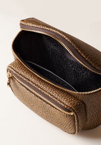 Pochette en cuir texturé marron avec des fermetures éclair dorées, un compartiment principal ouvert montrant une doublure intérieure noire avec un motif subtil.