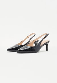 Cizme slingback din piele patentă neagră, cu vârful ascuțit, textură decorativă cu quilt și un toc subțire, de înălțime medie.