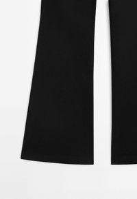 Partie inférieure d'un pantalon noir à jambes larges avec un ourlet proprement cousu sur fond blanc.