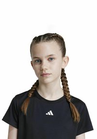 Schwarzes, kurzärmliges Sportshirt mit einem weißen Adidas-Logo; das Model hat geflochtene Haare und einen neutralen Gesichtsausdruck vor einem weißen Hintergrund.