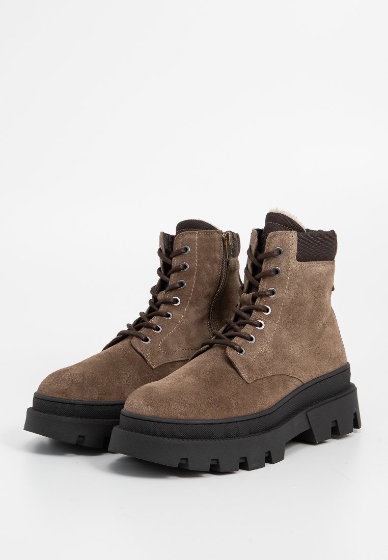 Bottines en suède marron à lacets avec semelles en caoutchouc noir épaisses et zips sur les côtés, dotées de cols rembourrés noirs et de détails cousus.