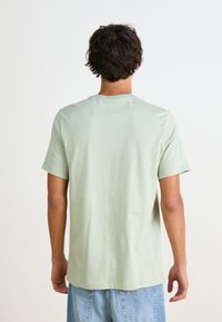 Ljusgrön kortärmad t-shirt i mjuk bomull, med rundad halsringning och rak passform. Baksidan har en slät yta utan synliga mönster.