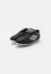 Black soccer cleats made of synthetic leather, featuring a quilted texture, white accents, and metal studs on the outsole for traction.