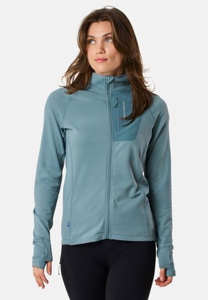 Light blue zip-up jacket with a high collar, featuring a chest pocket, fitted design, and thumbholes on the cuffs.
