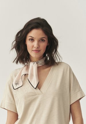 Ljust beige V-ringad topp med korta ärmar och strukturella detaljer; prydd med en ljusrosa scarf med svarta ränder och ett bi-motiv.