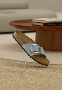 Μπλε σανδάλι τύπου slip-on με φαρδιά λουριά και μεταλλική αγκράφα, πάτος από φελλό και υφασμένη μαύρη λαστιχένια σόλα. Σχεδιασμένο για άνεση και καθημερινή χρήση.